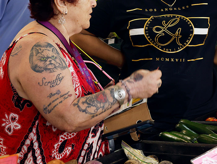 Walmart employee with colorful tattoos working produce section, capturing wild times employees felt underpaid at Walmart.
