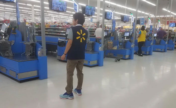 Walmart employees working at checkout lanes inside a store reflecting on challenging work moments and low pay.
