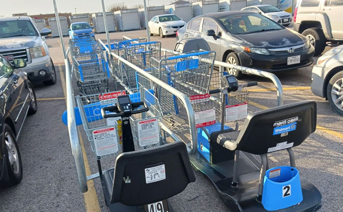 Walmart shopping carts and motorized carts lined up in a parking lot, representing wild times for Walmart employees.
