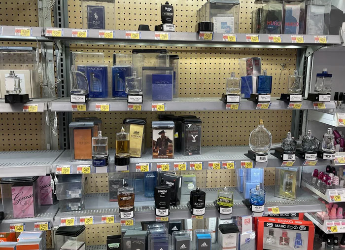 Partially empty Walmart perfume shelves showing various fragrance bottles and price tags during busy employee shifts.