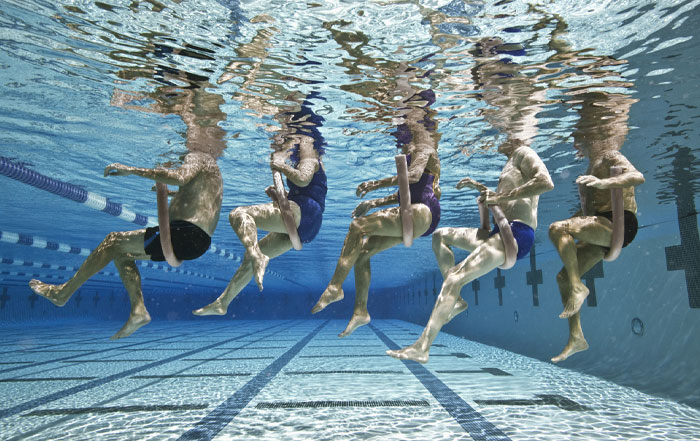Group of people underwater in a swimming pool, demonstrating water exercises and movement, relatable for water sign traits.
