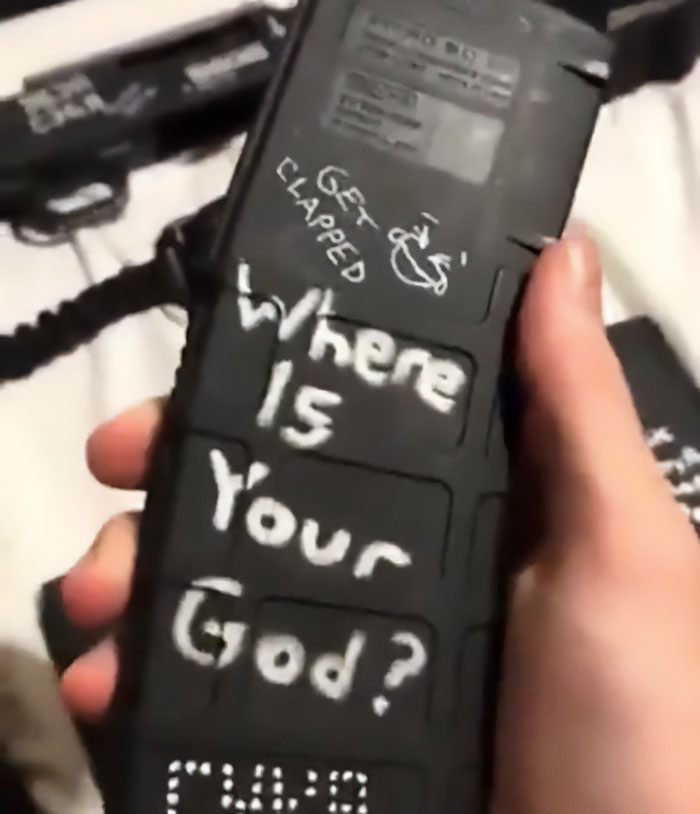 Hand holding a black magazine with disturbing white text written on it related to Minneapolis massacre culprit manifesto.