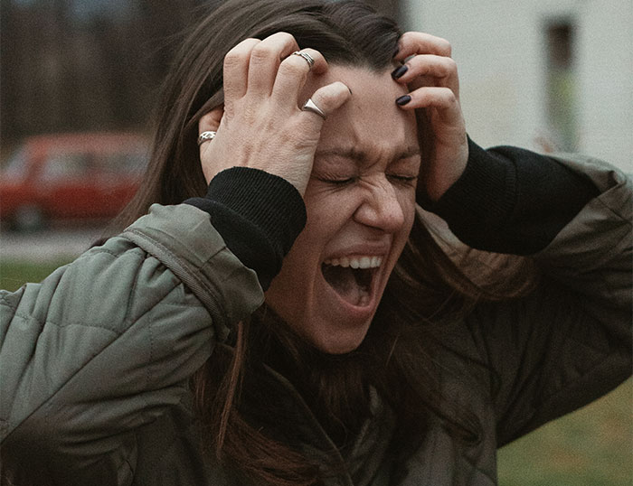 Frustrated woman holding her head in pain, illustrating BIL’s nightmare ex disrupting family events and wedding plans. - 7