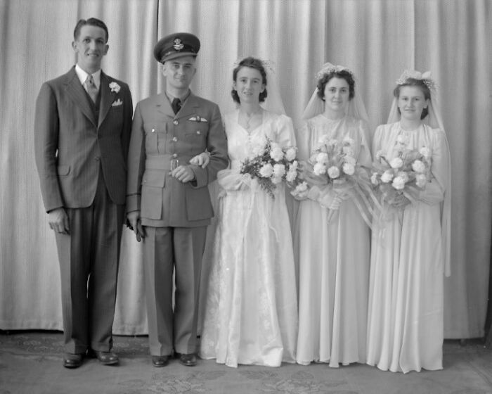 1940s wedding photo showing bride, groom in military uniform, bridesmaids with bouquets in a moving love in the shadow of war scene