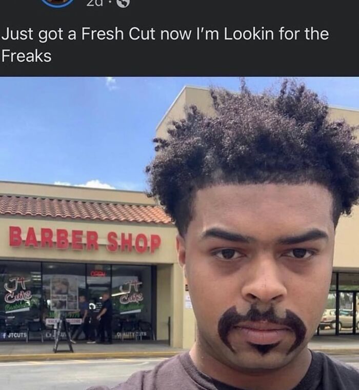Young man with a fresh haircut and unusual facial hair standing in front of a barber shop, cursed images style humor