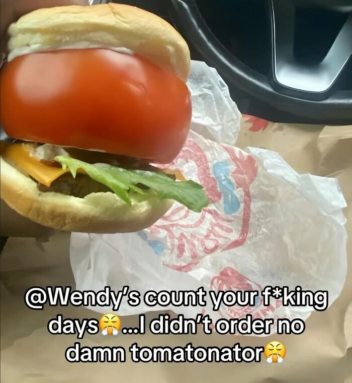 Close-up of a burger with an oversized tomato, part of a cursed image disturbing fans on Instagram.