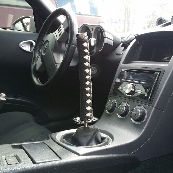 Car interior with a katana-style gear shift lever, an example of cursed images from a popular Instagram page.