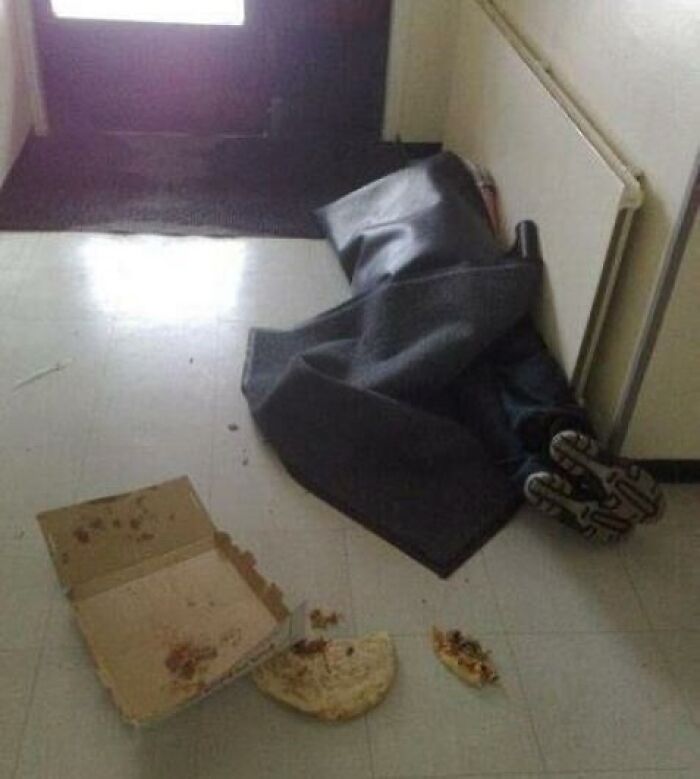 Person hidden under a dark blanket lying on the floor near a spilled pizza, cursed image from popular IG page disturbing fans