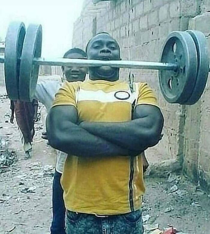 Man with arms crossed holding a heavy barbell in his mouth, a cursed image from a popular Instagram page disturbing 200K fans.