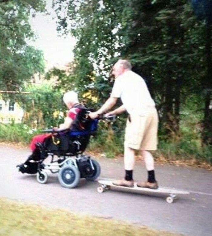 Man pushing person in wheelchair while riding a skateboard in a park, a cursed image disturbing many on Instagram.