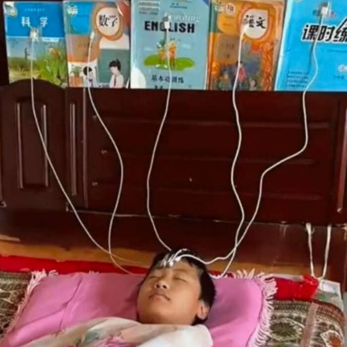 Child lying on a pillow with multiple charging cables attached to their head, creating a cursed image effect.