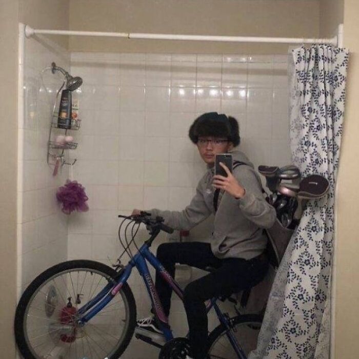 Young man taking a selfie while sitting on a bicycle inside a bathroom, a cursed image trending on an IG page.