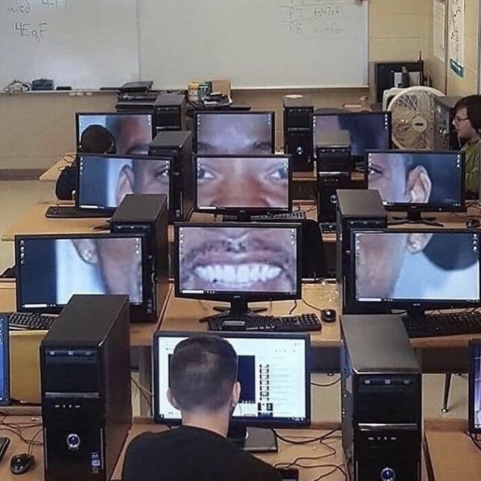 Classroom full of desktop computers displaying distorted close-up faces creating a cursed images effect for social media fans.