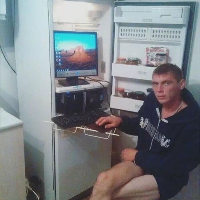 Man using a computer setup inside an open refrigerator, showcasing a cursed image from a daily cursed images Instagram page.