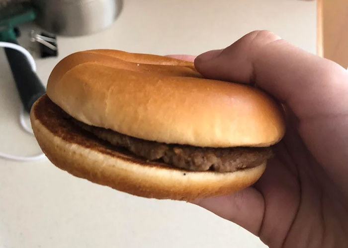 Hand holding a plain hamburger with a beef patty, illustrating something people assumed everyone did in their family.