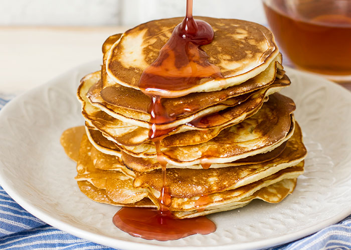 Stack of golden pancakes with syrup pouring over, illustrating family food traditions people assumed everyone did.