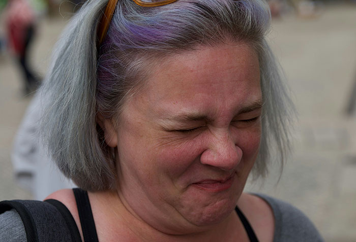 Woman with gray hair and purple highlights making a surprised face, illustrating parents accidentally uncovering a side of their kids.