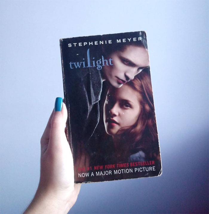 Hand holding a worn Twilight book, illustrating snooping parents discovering unexpected sides of their kids.