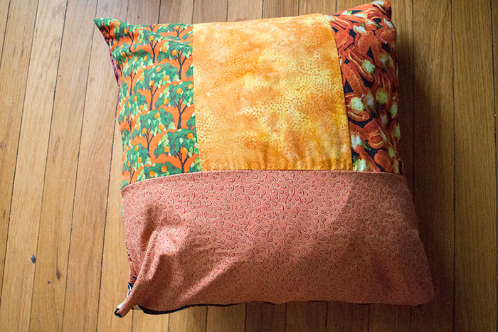 Patchwork pillow with autumn colors resting on a wooden floor, illustrating unexpected discoveries by snooping parents.