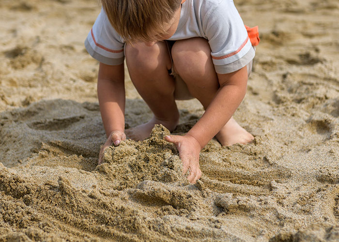 Child playing in the sand, illustrating the kind of madness that some people have to witness at work.