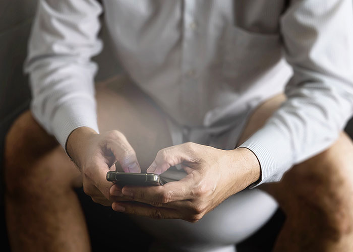 Man in a white shirt using smartphone, illustrating people dealing with madness they witnessed at work moments.