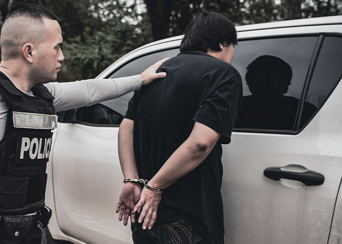 Police officer handcuffing a man near a car, representing chaos and madness people had to witness at work.