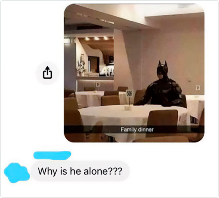 Person dressed as Batman sitting alone at a restaurant table, illustrating a missed joke and embarrassing moment.