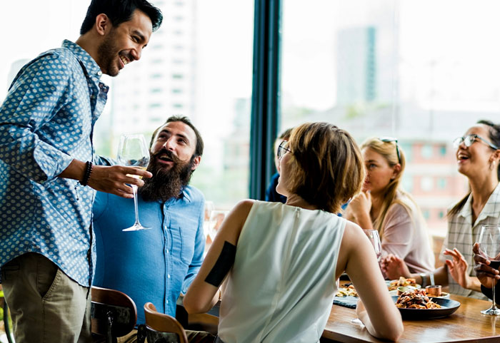 Group of coworkers socializing around a table with drinks, highlighting inappropriate work comments and potential discipline issues.