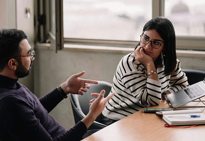 Wife listening in disbelief as husband explains facing discipline again for inappropriate work comments in office setting