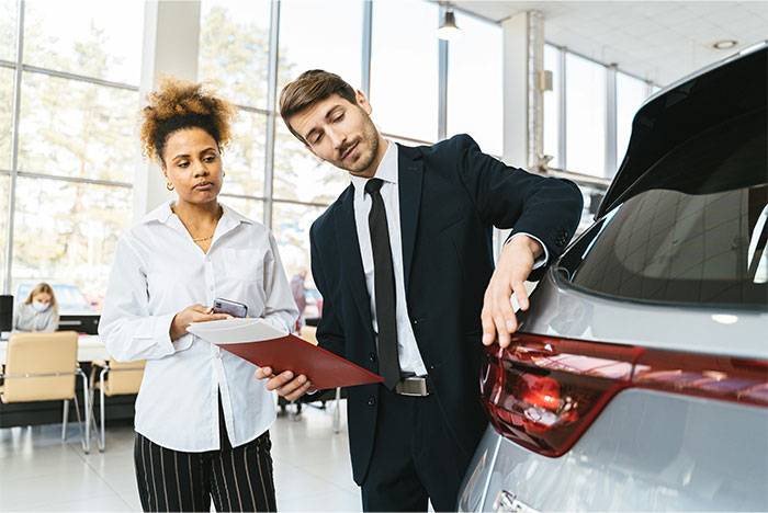 Husband dragging wife out of car dealership before she can show him the car she wants in modern showroom.