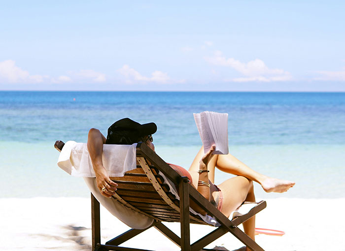 Person relaxing on a beach chair by the sea, representing Emokoyee not showing up to a meet due to being off.