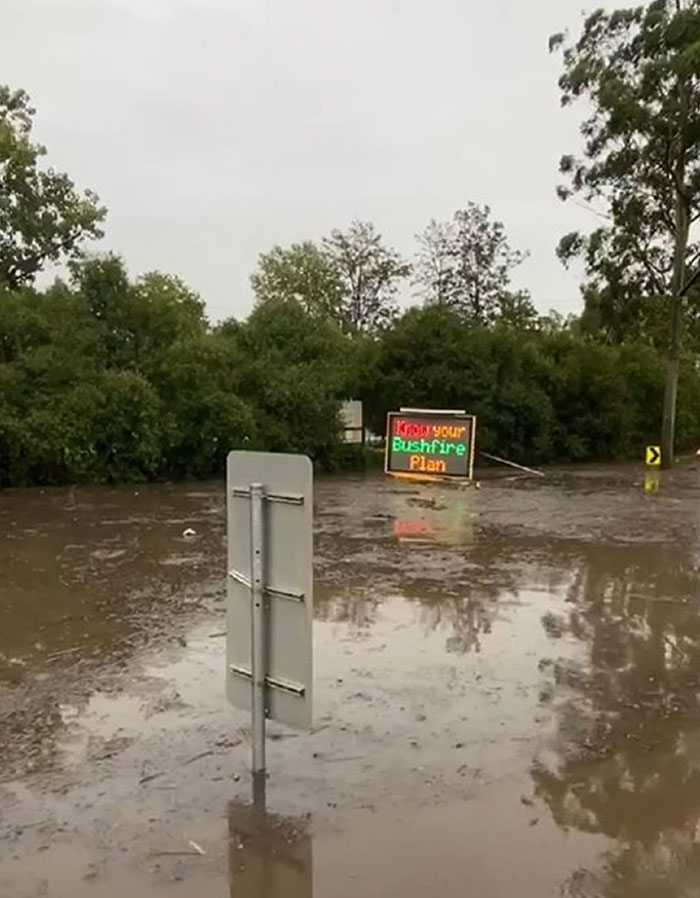 Flooded area with muddy water covering roads and traffic signs, showcasing wild Mother Nature doing things on its own terms.