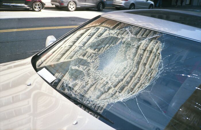 Car windshield with a large shattered impact area, symbolizing people surviving crazy situations and accidents.