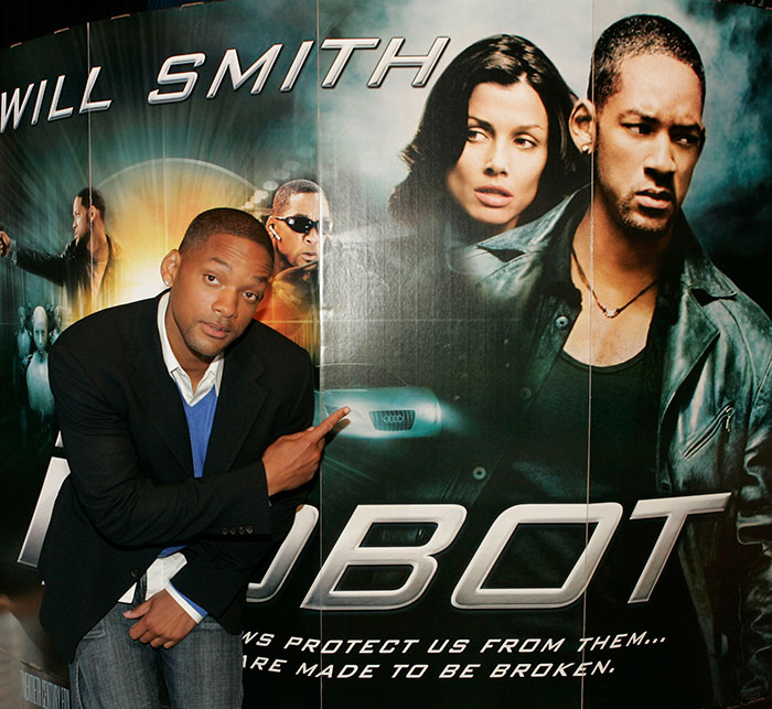 Will Smith posing next to a Robo movie poster, related to co-actor accusing studio of name removal claim.