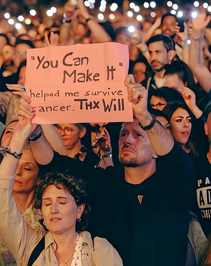 Crowd holding a sign at a concert, with many hands raised in the air, highlighting Will Smith and AI discussions. Crowd holding a sign at a concert, with many hands raised in the air, highlighting Will Smith and AI discussions.