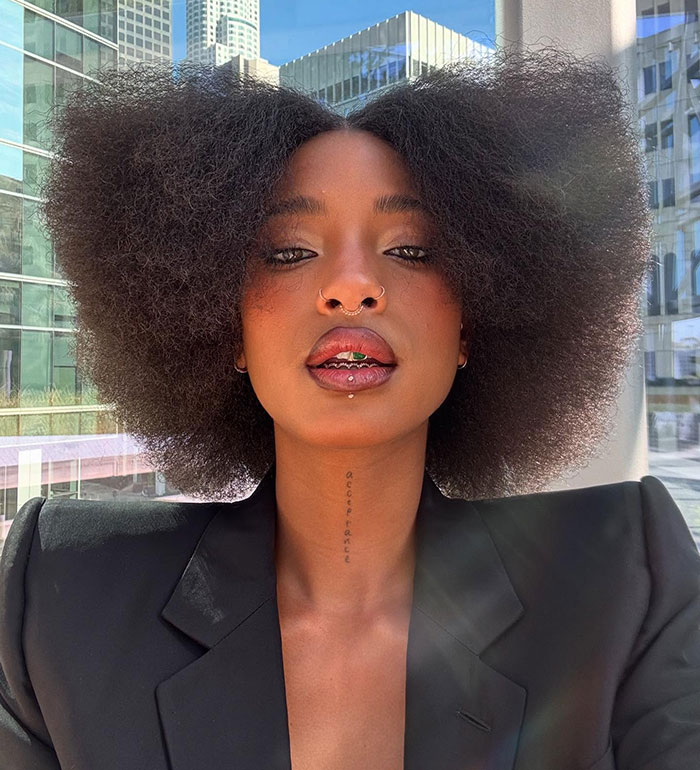 Will Smith and Jada Pinkett's daughter with natural afro hairstyle and piercings in an outdoor urban selfie.