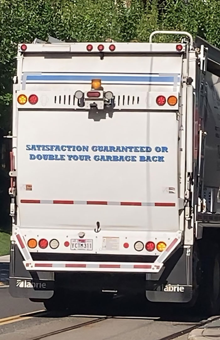Garbage truck with witty slogan promising satisfaction or double your garbage back on the rear door.