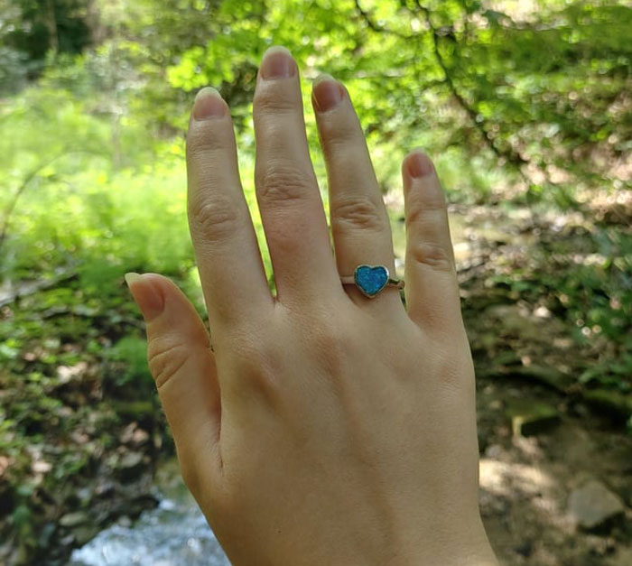 Hand wearing a heart-shaped ring outdoors, symbolizing a woman accepting her AI boyfriend&rsquo;s proposal.