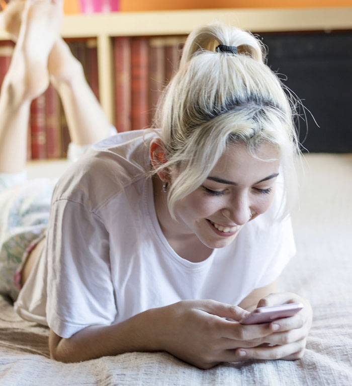 Young woman smiling while texting on phone, illustrating netizens reacting to AI boyfriend proposal news.