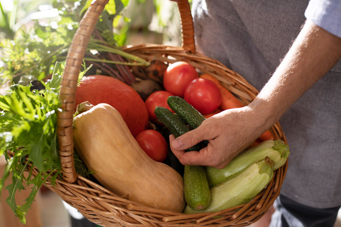 Person holding a basket of fresh vegetables, highlighting a thief caught stealing vegetables from the owner.