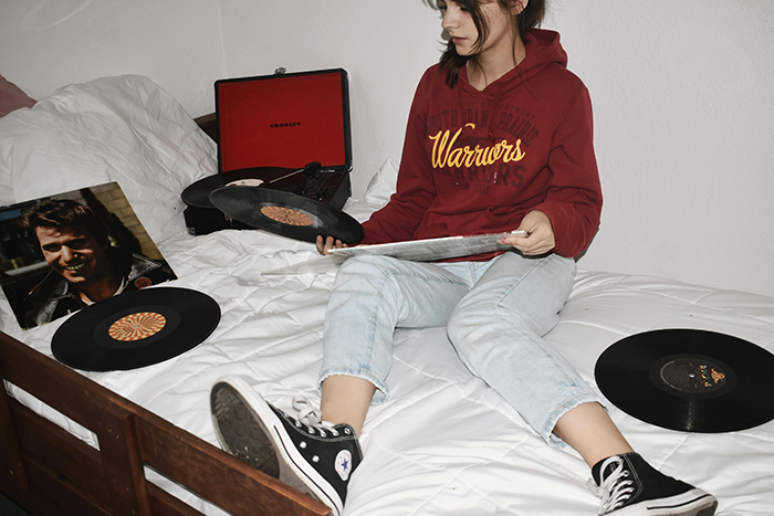 Woman handling vinyl records on bed, representing temporary houseguest and paying for missed payments aftermath. Woman handling vinyl records on bed, representing temporary houseguest and paying for missed payments aftermath.