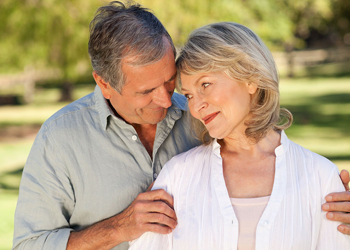 Middle-aged couple sharing a tender moment outdoors, representing parents breaking heart with needy behavior after daughter moves out. Middle-aged couple sharing a tender moment outdoors, representing parents breaking heart with needy behavior after daughter moves out.
