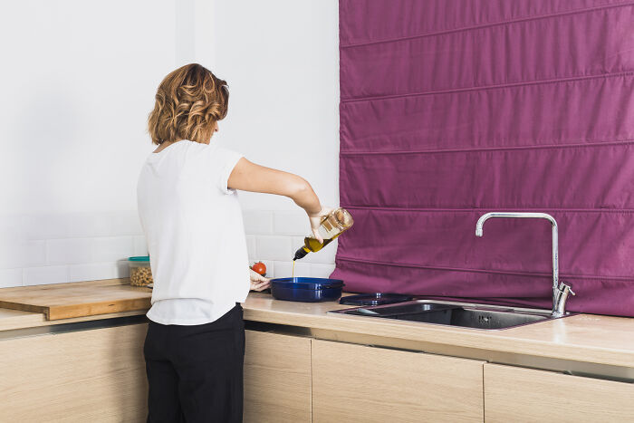 Woman pouring oil into a pan in a modern kitchen, illustrating words that don’t exist in English but used in other languages.