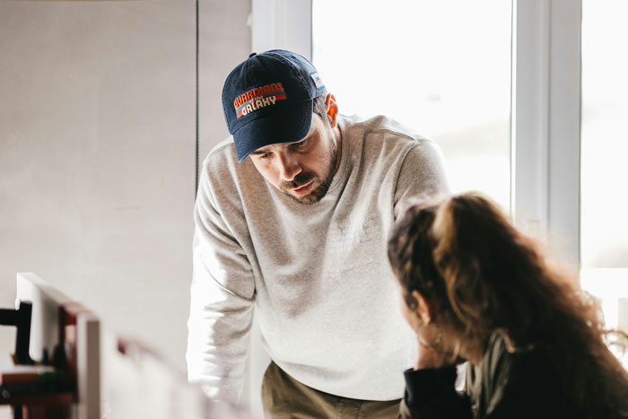A man hiding an affair talks seriously with a woman in a bright room, reflecting tension about the secret and new family roles. A man hiding an affair talks seriously with a woman in a bright room, reflecting tension about the secret and new family roles.