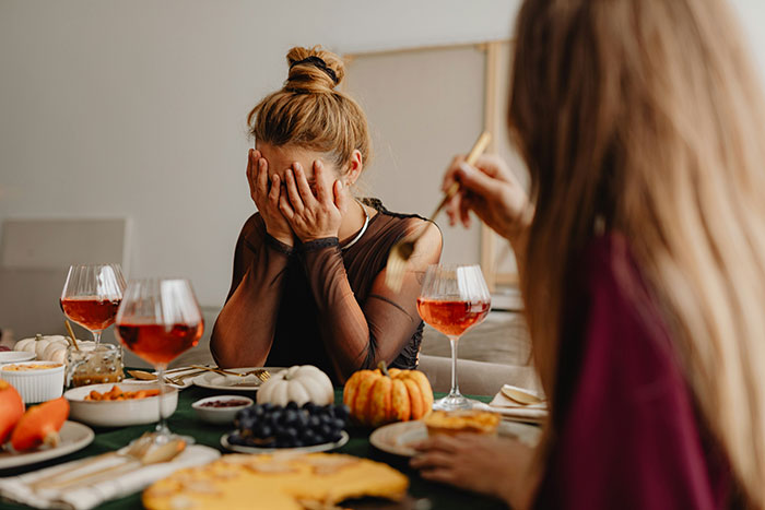 Woman with hands covering face at family dinner, showing distress and lack of support after devastating news and SIL drama.