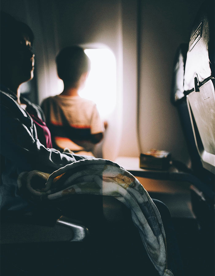 Passenger and child on flight, child looking out window, highlighting passenger's worst experience with bored child in flight debate.