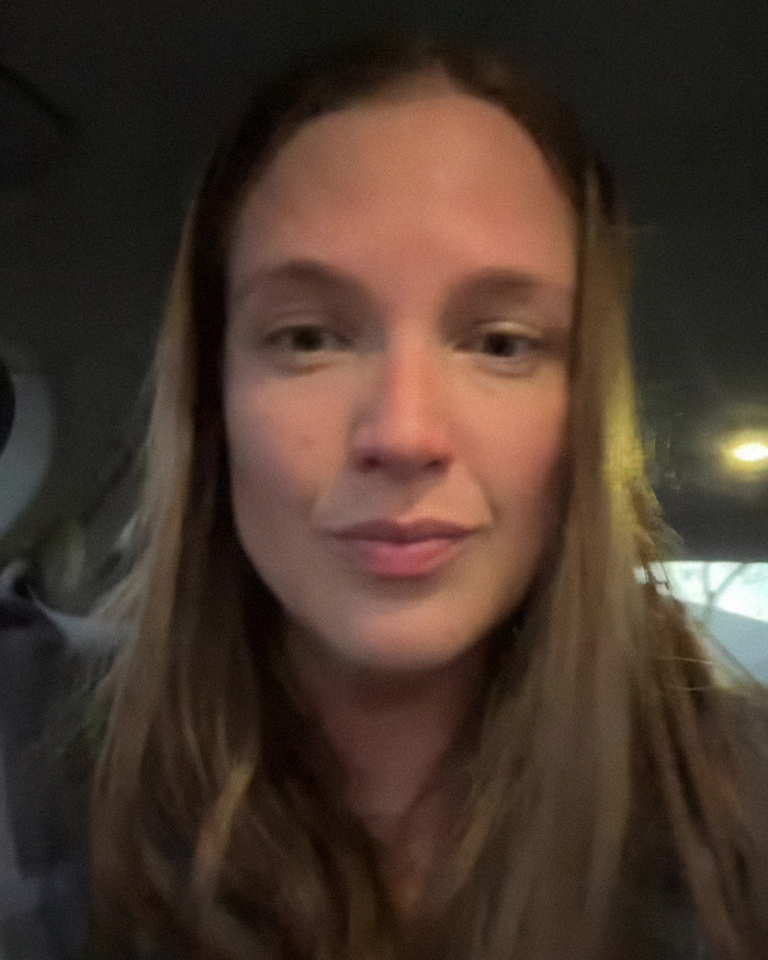 Woman with long hair inside a car, sharing her story about getting violent after falling in love with therapist online.