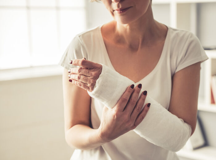 Woman with arm cast holding her forearm indoors highlighting cool facts about the human body.