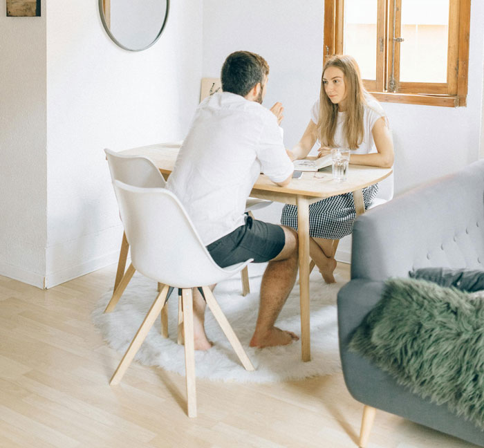 Couple having a serious discussion at home, highlighting postpartum trip issues and family dynamics.