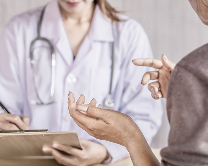 Woman showing smart ring to doctor during consultation about early illness detection and health monitoring.